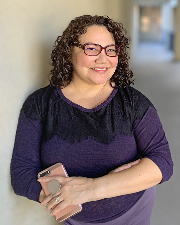 Paulette in a black and purple sweater smiling at the camera